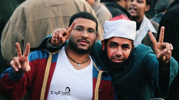 Coptic Christian and Islamic imam raise their fingers in a sign of victory